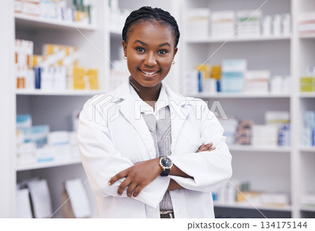 Pharmacy, pharmacist or portrait of black woman with arms crossed or smile in healthcare drugstore or clinic. Face, hospital or happy doctor smiling by medication or medicine on shelf ready to help 134175144