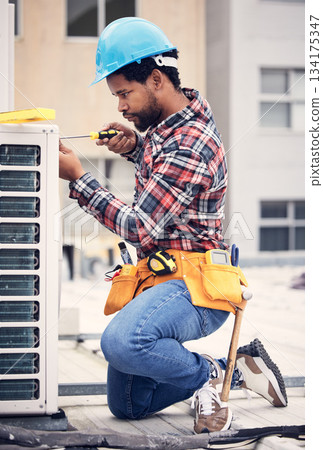 Black man, electrician and maintenance with engineer and ac repair with handyman working with tools on roof. Fix air conditioner, male technician with screwdriver and power generator with service 134175347