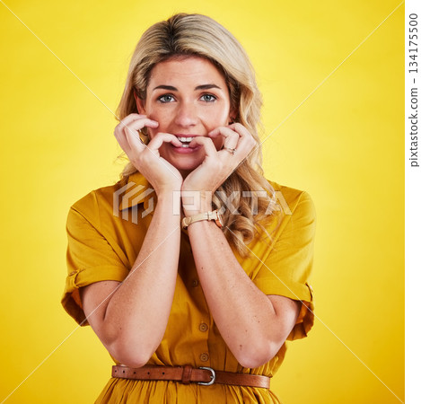 Stress, biting nails and woman portrait in a studio with anxiety and fear from news. Isolated, yellow background and scared female person with panic and thinking with a nervous and worried feeling 134175500
