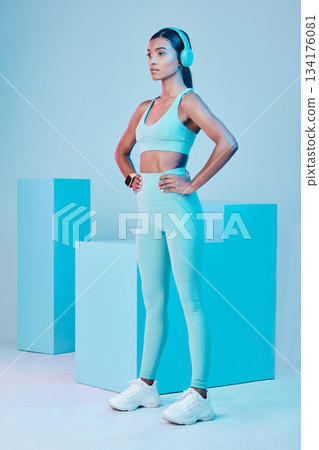 Focus, active and a woman with headphones for fitness motivation isolated on a studio background. Ready, gym and an Indian girl preparing for a workout with music, podcast or radio for empowerment 134176081