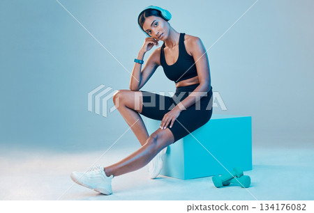 Portrait, fitness and woman with wellness, exercise and training for energy, headphones and focus on a blue studio background. Face, female athlete and person with headset, workout goals and mindset 134176082