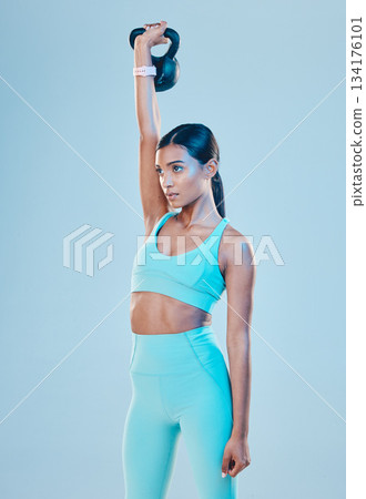 Kettlebell, exercise and woman training, fitness and focus for wellness, healthy lifestyle and cardio against a blue studio background. Female athlete, model and person with gym equipment and strong 134176101