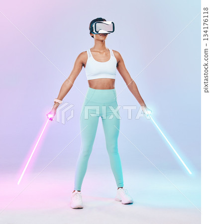 Fitness, virtual reality glasses and woman with lightsaber, futuristic and player against studio background. Female gamer, person or confident girl with vr eyewear, fantasy weapons and laser saber 134176118