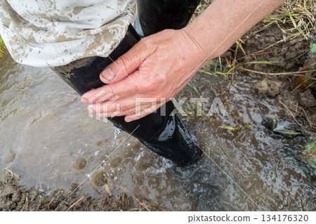 Washing off dirt from boots soiled by rice planting with rice field water Washing off dirt from boots soiled by rice planting with rice field water 134176320