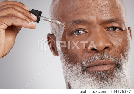 Skincare, portrait and male with face oil in a studio for a natural, beauty and skin treatment. Cosmetic, health and senior man model with facial serum for a wellness routine by a gray background. 134176387
