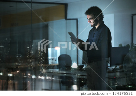 Business man, tablet and smile in office, online browsing or internet scroll by window with city lights at night. Technology, happiness and professional person with touchscreen for research deadline. 134176551
