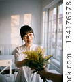 A Japanese woman smiles happily after receiving mimosa flowers 134176578