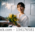 A Japanese woman smiles happily after receiving mimosa flowers 134176581