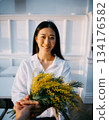 A Japanese woman smiles happily after receiving mimosa flowers 134176582