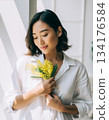 A Japanese woman smiles happily after receiving mimosa flowers 134176584