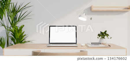 Blank screen laptop and calculator with lamp on wooden table aside white wall and green houseplant. 134176602