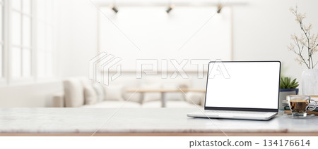 White screen laptop and coffee on marble table across sofa and blank frame on wall with ceiling lamp White screen laptop and coffee on marble table across sofa and blank frame on wall with ceiling lamp 134176614