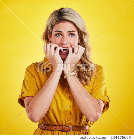 Portrait, biting nails and woman in studio with anxiety, nervous and afraid against yellow background. Panic, fear and face of lady with bad habit, phobia and stress, scared and worried about mistake Portrait, biting nails and woman in studio with anxiety, nervous and afraid against yellow background. Panic, fear and face of lady with bad habit, phobia and stress, scared and worried about mistake 134176669