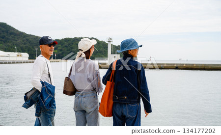 Three people looking at the view at the harbor Three people looking at the view at the harbor 134177202