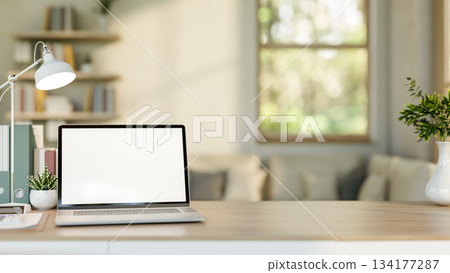 Blank screen laptop with file folder and cactus aside lamp on wooden table in living room or office. Blank screen laptop with file folder and cactus aside lamp on wooden table in living room or office. 134177287