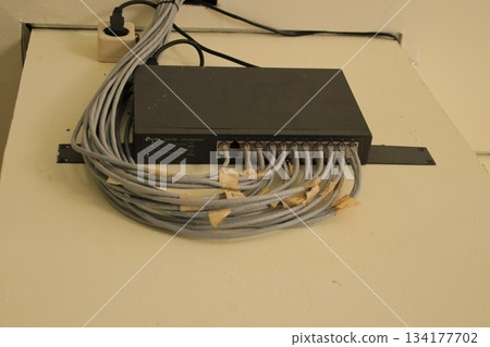 Black network switch connected to many gray Ethernet cables. Black network switch connected to many gray Ethernet cables. 134177702