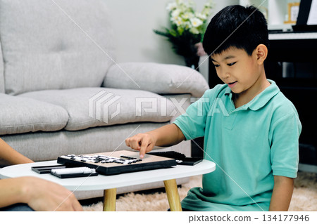 young boy concentrating while playing Go at home, pointing to a move on the board during a thoughtful and educational indoor activity that encourages logic, patience, and cognitive development young boy concentrating while playing Go at home, pointing to a move on the board during a thoughtful and educational indoor activity that encourages logic, patience, and cognitive development 134177946
