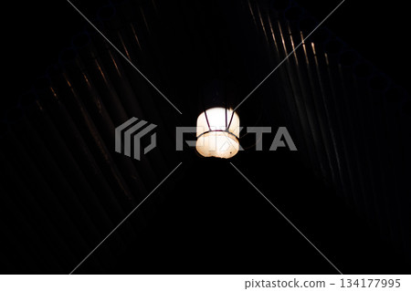 Old hanging industrial light fixture illuminating dark ceiling background Old hanging industrial light fixture illuminating dark ceiling background 134177995