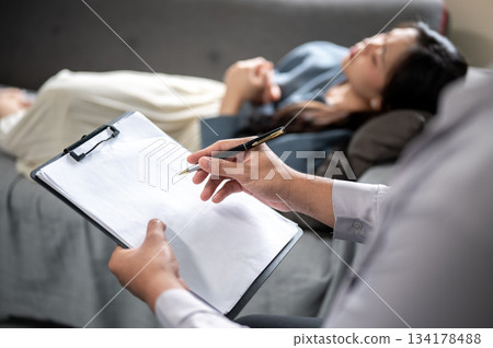 Close up of doctor's hands holding pen over clipboard writing patient's condition in diagnosis room. 134178488