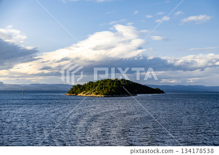 Tranquil Island Surrounded by Deep Blue Sea Under Dramatic Clouds Tranquil Island Surrounded by Deep Blue Sea Under Dramatic Clouds 134178538