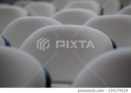 Close-up abstract pattern of beige auditorium seats showing curved backs and textured fabric. 134179529