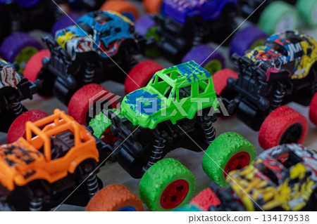 Close up view of bright colorful plastic monster trucks toys collection background for childrens playing fun Close up view of bright colorful plastic monster trucks toys collection background for childrens playing fun 134179538