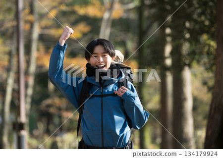 A man pumping his fist after enjoying a hike through autumn and winter foliage, looking at the camera A man pumping his fist after enjoying a hike through autumn and winter foliage, looking at the camera 134179924