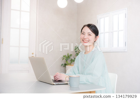 Smiling cute woman using a computer at home or in a cafe, looking at the camera 134179929