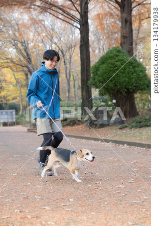 一位微笑的男子在秋日的公園帶著他的狗散步,享受著與寵物相處的時光。 一位微笑的男子在秋日的公園帶著他的狗散步,享受著與寵物相處的時光。 134179938