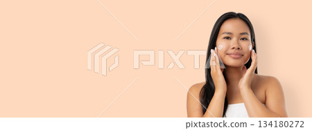 Woman cares for her skin in a wellness space with soft colors 134180272