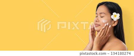 Woman enjoys a skincare routine with a flower accessory 134180274