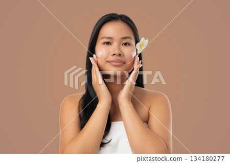 Woman cares for her skin with a product on her face 134180277