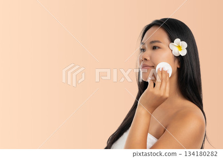 Woman uses cotton pad for skincare at a spa location 134180282