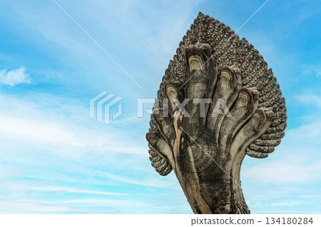 Low angle close up view of seven headed Naga serpent stone statue against blue sky background at ancient Khmer temple entrance bridge Low angle close up view of seven headed Naga serpent stone statue against blue sky background at ancient Khmer temple entrance bridge 134180284