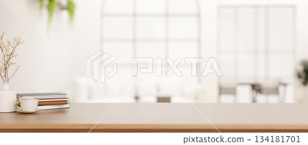 A cup of coffee and books aside flower vase on wooden counter table in bright living room or library 134181701