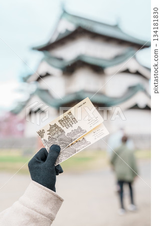 Tourist hand holding Hirosaki castle ticket during sightseeing Sakura Cherry Blossom in Spring season at Hirosaki Castle park. Hirosaki city, Aomori prefecture, Tohoku, Japan, 25 April 2025 134181830