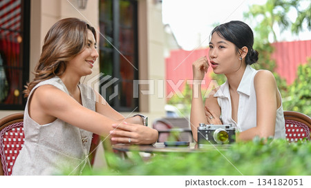 Asian woman talking with friend over camera sitting at wooden table in front of a cafe or restaurant Asian woman talking with friend over camera sitting at wooden table in front of a cafe or restaurant 134182051