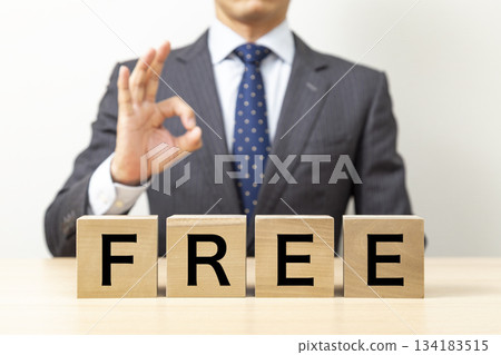 一位商人擺出「OK」的手勢,手裡拿著一個寫著「免費」的方塊。 一位商人擺出「OK」的手勢,手裡拿著一個寫著「免費」的方塊。 134183515