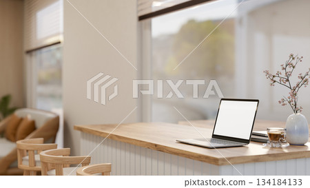 White screen laptop with coffee and book on counter table aside glass window in living room or cafe 134184133