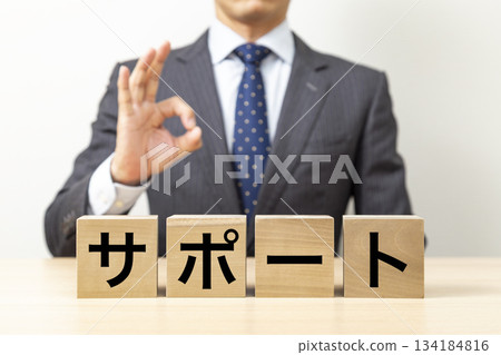 A businessman making an OK pose with a block that says "support" 134184816