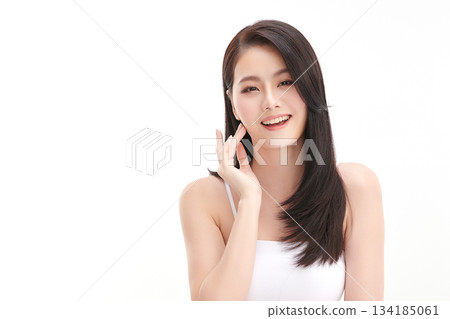 A beautiful young Asian woman with clean, fresh skin against a white background. Skincare, facial treatment, cosmetology, beauty, and spa. An elegant portrait of an Asian woman. 134185061