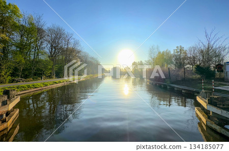 A Serene Sunrise that Spreads Beauty Over a Picturesque Canal Surrounded by Lush Greenery 134185077