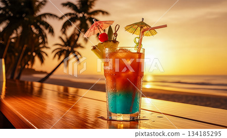 Tropical cocktail glass with umbrella and fruit on wooden bar counter against beautiful ocean sunset background during summer vacation 134185295