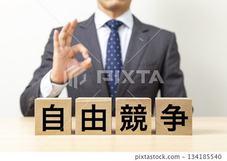 一位商人擺出「OK」的姿勢,旁邊立著一塊寫著「自由競爭」的牌子。 一位商人擺出「OK」的姿勢,旁邊立著一塊寫著「自由競爭」的牌子。 134185540