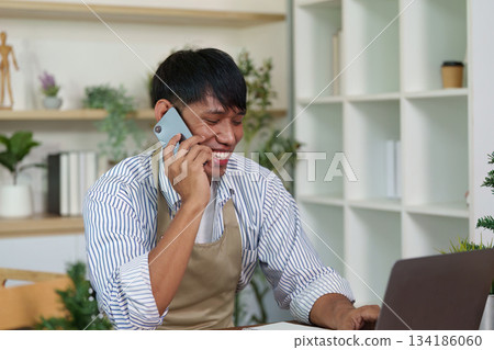 Communication and Connection. A cheerful man talking on the phone while working on a laptop. Communication and Connection. A cheerful man talking on the phone while working on a laptop. 134186060