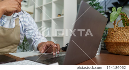 Focus and Technology. A close-up of a person contemplating while working on a laptop in a modern office. Focus and Technology. A close-up of a person contemplating while working on a laptop in a modern office. 134186062