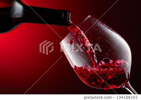 Red wine is poured from a bottle into a glass. 134186101