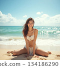 Woman in swimsuit sitting on sandy beach 134186290