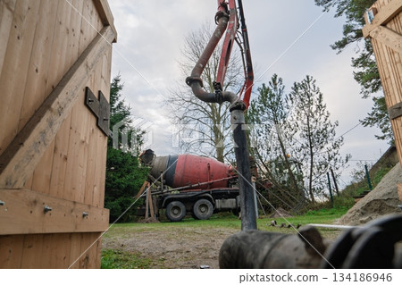 Concrete Mixer Truck Pumping Cement on Construction Site with Wooden Structures Around Concrete Mixer Truck Pumping Cement on Construction Site with Wooden Structures Around 134186946
