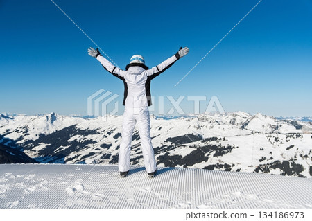Exhilarating Alpine Vista Woman Embracing Freedom in Snowy Mountain Landscape. 134186973